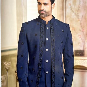 May include: A navy blue suit jacket with intricate black embroidery and embellishments. The jacket features a mandarin collar and a button-down front. The suit is a formal style, suitable for special occasions.