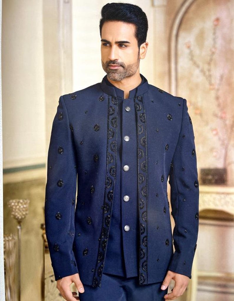 May include: A navy blue suit jacket with intricate black embroidery and embellishments. The jacket features a mandarin collar and a button-down front. The suit is a formal style, suitable for special occasions.