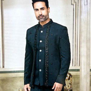 May include: A dark teal suit with a mandarin collar. The jacket features decorative beading along the front and sleeves, with silver buttons. The suit is a formal ensemble, suitable for special occasions.