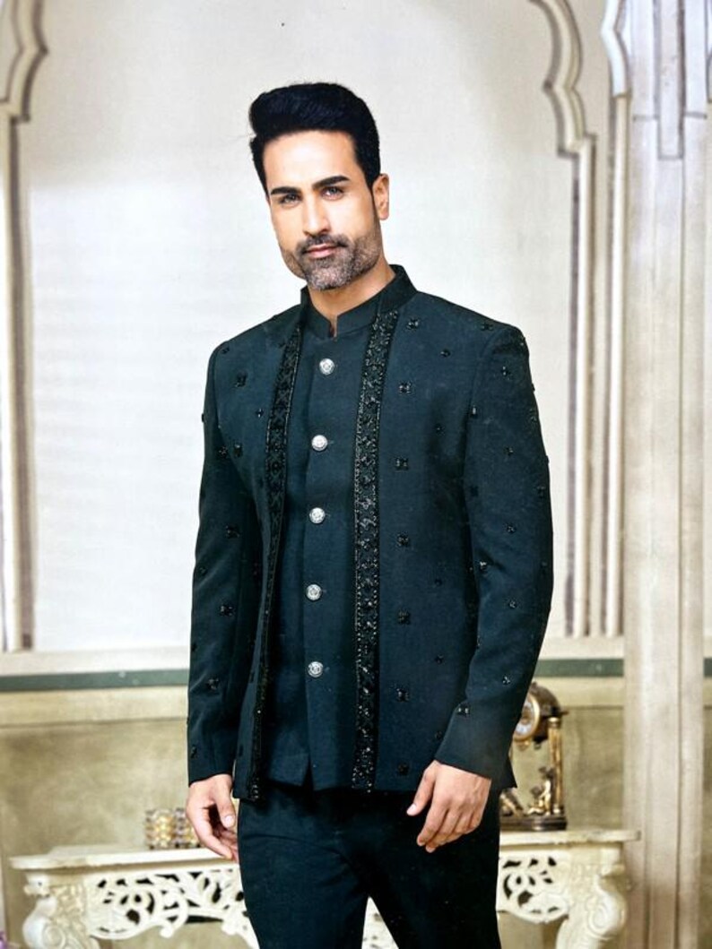 May include: A dark teal suit with a mandarin collar. The jacket features decorative beading along the front and sleeves, with silver buttons. The suit is a formal ensemble, suitable for special occasions.