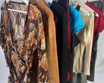 May include: A rack of clothing with a variety of styles and colors, including a brown and orange patterned top, a brown suede jacket, a black and red patterned top, a black jacket, a blue and white striped shirt, a beige shirt, and a brown skirt.