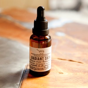 Puede incluir: Una botella de vidrio marrón con un gotero y una etiqueta blanca que dice "RADIANT SKIN" con el texto "clair viso luminoso" debajo. La etiqueta también incluye el texto "PREPARAZIONE NATUROPATICA ALLE PIANTE CHE CURANO".