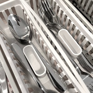 May include: White plastic cutlery organizer with multiple compartments for storing forks, spoons, and knives. The organizer is filled with silverware.