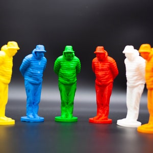 Può includere: Sei piccole figurine di persone che indossano cappelli e giacche, in piedi in fila. Le figurine sono dipinte in diversi colori: giallo, blu, verde, rosso, bianco e arancione.