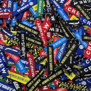 May include: A collection of colourful airplane keychains with various airline logos and the text "Remove Before Flight".