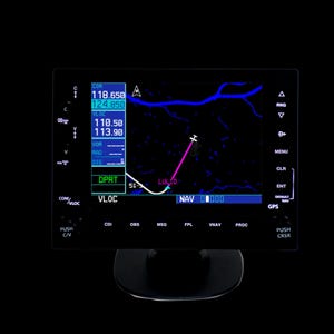 May include: A black aviation instrument panel displaying flight data, including frequencies and navigation information. The screen shows a flight path with a pink line and the text "LUL TO". The panel has various buttons and labels.