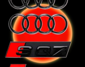 May include: Black and chrome Audi emblems and SQ7 badges against a red and black background. The Audi rings are stacked above the SQ7 emblems. The SQ7 badges have a red background with black lettering.