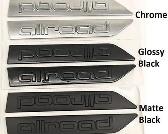 May include: A product image showcasing car emblems in three different finishes: chrome, glossy black, and matte black. Each finish features the word "allroad" in a stylized font. The chrome emblems are silver, while the black emblems are in pairs.