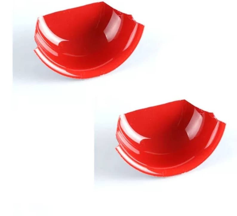 May include: Two red plastic bowls with a chipped edge. The bowls are shallow and have a glossy finish.