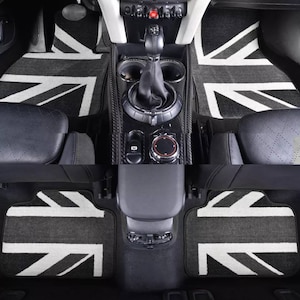 Op de afbeelding: Zwart-witte Union Jack autovloermatten met een grijze achtergrond. De matten zijn gemaakt van een zacht, pluche materiaal en hebben een verhoogd Union Jack-ontwerp.