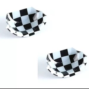 May include: Two black and white chequered car emblems. The emblems are made of plastic and have a slightly curved shape.
