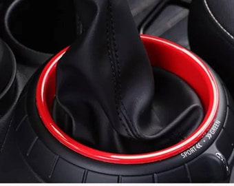 May include: Red and white gear shift knob ring with the text "SPORT <<  >> GREEN" on the side.