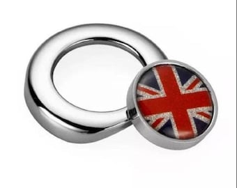 May include: A silver ring with a round, red, white, and blue Union Jack flag charm. The charm has a glittery finish.