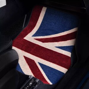 Op de afbeelding: Een autovloermat met een rood, wit en blauw Union Jack-ontwerp. De mat is gemaakt van een zacht, pluche materiaal.