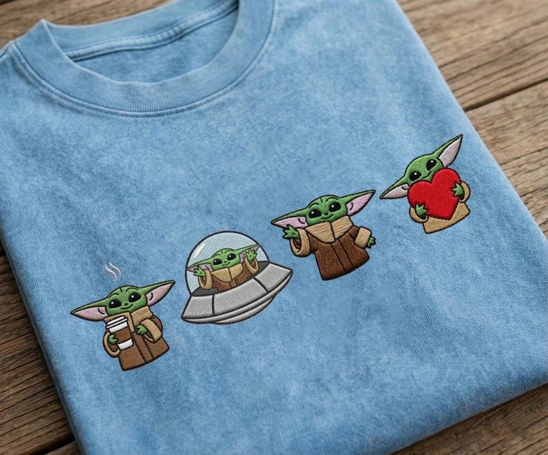May include: Light blue crew neck sweatshirt with embroidered images of a green alien character in various poses. The alien is holding a coffee cup, in a spaceship, gesturing, and holding a red heart.
