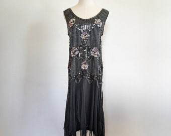 May include: A black sequined dress with a floral design. The dress has a sleeveless bodice and a flowing skirt with a scalloped hem.