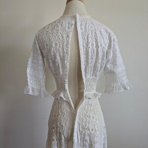 May include: White eyelet dress with a low back and a zipper closure. The dress has a fitted bodice and a flowing skirt.
