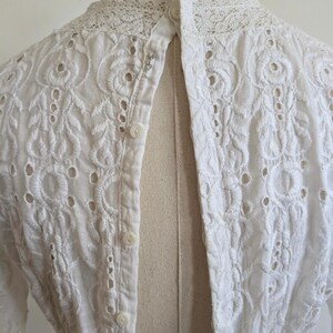 May include: White eyelet lace top with a button-up back and a lace collar.