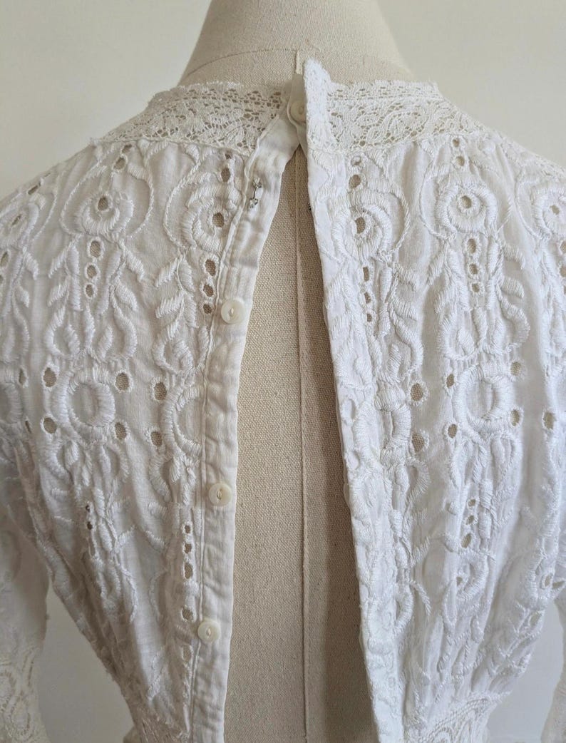 May include: White eyelet lace top with a button-up back and a lace collar.