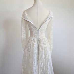 Puede incluir: Un vestido de novia de encaje blanco con mangas largas y una cremallera en la espalda.