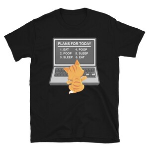 May include: Black t-shirt with a cartoon cat sitting in front of a laptop. The laptop screen displays a list of plans for the day: 1. Eat, 2. Poop, 3. Sleep, 4. Poop, 5. Sleep, 6. Eat.