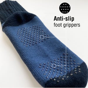 Puede incluir: Un par de calcetines azules con agarraderas antideslizantes negras para los pies. Las agarraderas est&aacute;n hechas de peque&ntilde;os puntos que cubren la parte inferior de los calcetines. El texto "Anti-slip foot grippers" est&aacute; escrito en negro sobre fondo blanco.