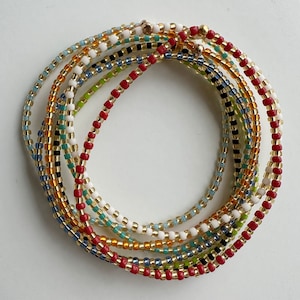May include: A multi-strand beaded bracelet with red, white, gold, blue, and green beads.