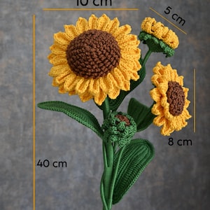Puede incluir: Un ramo de girasoles de ganchillo con una flor grande de 10 cm, una flor de 8 cm, un capullo de 5 cm y un pequeño capullo cerrado. Los tallos y las hojas son verdes y la altura total es de 40 cm. Los pétalos son amarillos con centros marrones.