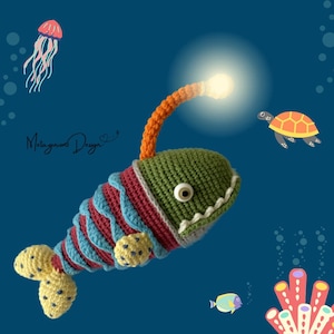 Puede incluir: Un juguete de pez pescador de crochet con un señuelo luminoso, rayas rojas, azules y amarillas y un cuerpo verde. El juguete nada en una escena de océano azul con un arrecife de coral, una tortuga y una medusa.