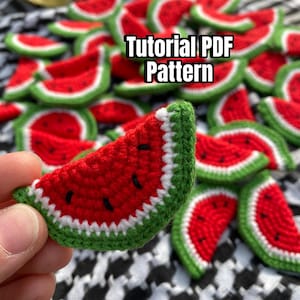May include: A close-up of a crocheted watermelon slice, with red and green yarn, held in a hand. The image is surrounded by a pile of other crocheted watermelon slices. The text "Tutorial PDF Pattern" is displayed on the image.