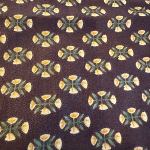 May include: A dark brown fabric with a repeating pattern of small yellow flowers with green leaves.