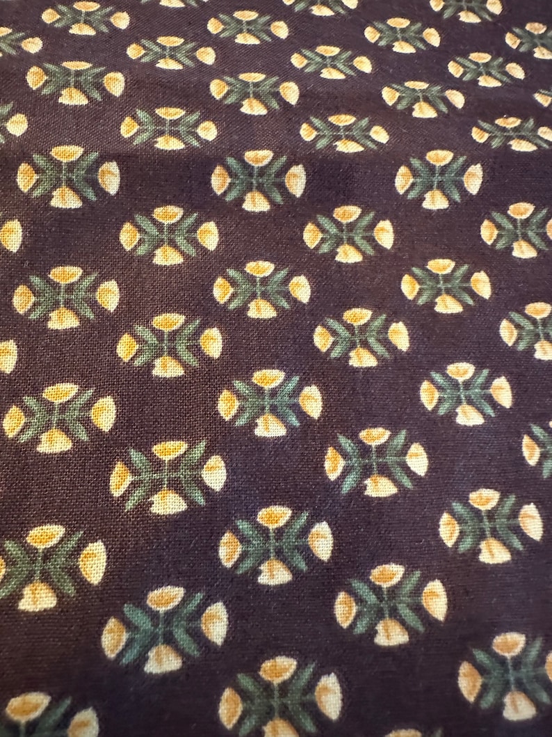 May include: A dark brown fabric with a repeating pattern of small yellow flowers with green leaves.
