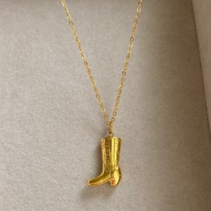 Op de afbeelding: Een gouden ketting met een gedetailleerd gouden laarsbedel.