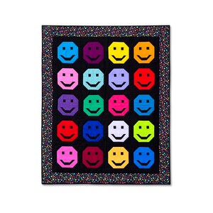 May include: A black and white quilt with a colorful pattern of smiling faces. The quilt is bordered with a black and white polka dot pattern.