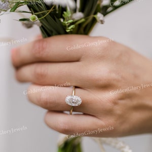Puede incluir: Primer plano de una mano con un anillo de oro con un diamante de forma ovalada.