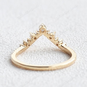 May include: A gold band ring with a V-shaped row of small diamonds. The ring is designed to be worn as a wedding band or a promise ring.