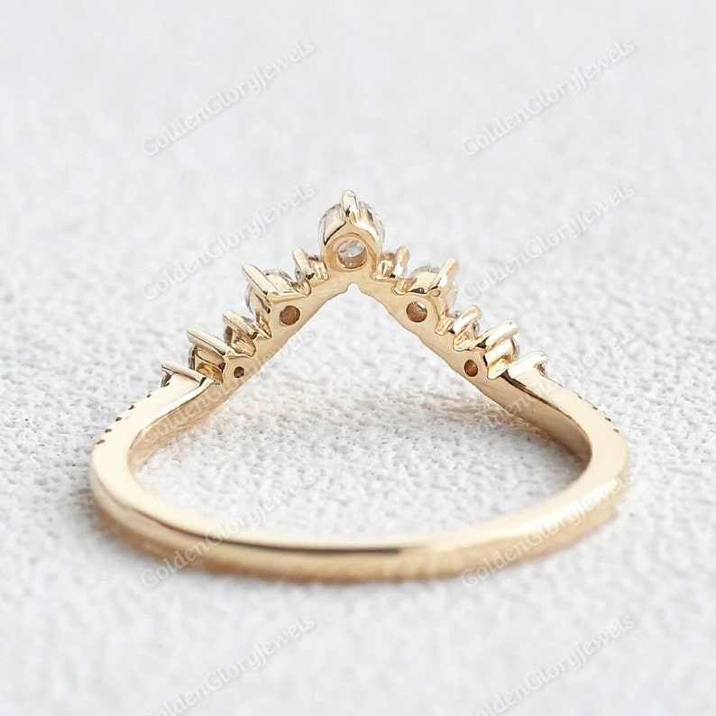 May include: A gold band ring with a V-shaped row of small diamonds. The ring is designed to be worn as a wedding band or a promise ring.