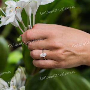 Puede incluir: Primer plano de una mano con un anillo de oro con un diamante de forma ovalada. El anillo est&aacute; engastado en una banda sencilla y el diamante brilla.