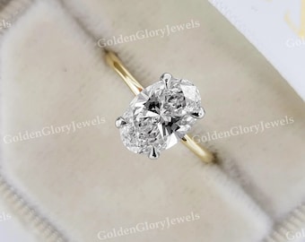 Könnte beinhalten: Ein goldener Verlobungsring mit einem großen ovalen Diamanten. Der Ring befindet sich in einer weißen Samtbox.