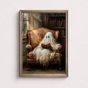 May include: A framed wall art print depicting a figure draped in a white sheet, resembling a ghost, sitting in a floral patterned armchair while reading an open book. The scene is set in a room with a bookshelf and a window with soft light.