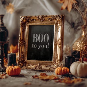 May include: A rectangular picture frame with an ornate gold finish containing a black chalkboard surface. The text "BOO to you!" is written in white lettering on the center of the chalkboard. The frame features intricate scrollwork and relief details.