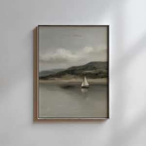 May include: A framed landscape painting depicts a sailboat on a calm lake. The artwork features a muted color palette of gray, green, and beige, with a cloudy sky and rolling hills in the background. The painting is in a silver frame.