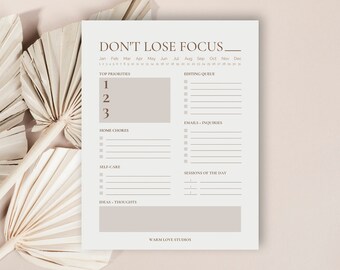 May include: A printable daily planner with a light gray background and brown text. The planner includes sections for top priorities, editing queue, emails and inquiries, home chores, self-care, sessions of the day, and ideas and thoughts. The text "DON'T LOSE FOCUS_" is at the top of the page.