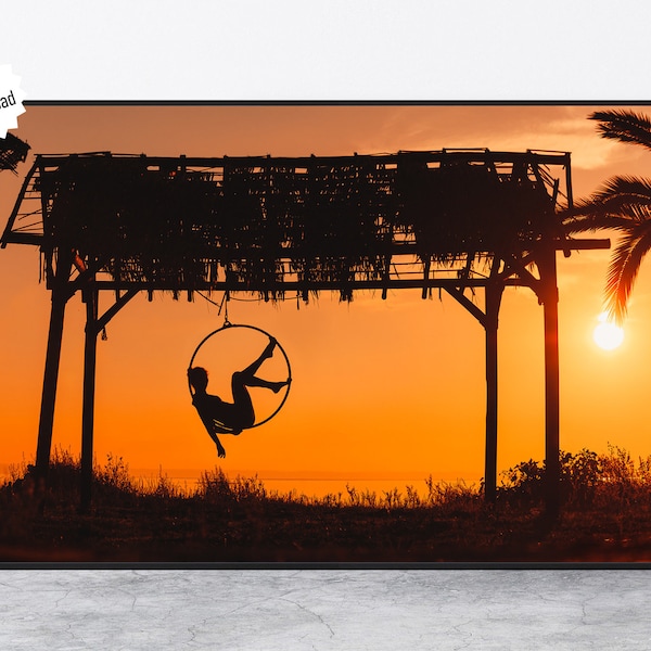 Digital file a silhouette portrait of a female dancer posing on an aerial hoop at a summer beach under a kiosk at sunset, Halkidiki Greece