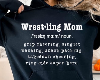 May include: Black hooded sweatshirt with the text "Wrestling Mom /'reslın ma:m/ noun. grip cheering, singlet washing, snack packing, takedown cheering, ring side super hero." printed in white.