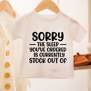 May include: White baby onesie with black text that reads "Sorry - The sleep you've ordered is currently stock out of".