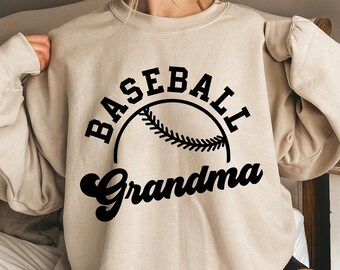 May include: Beige sweatshirt with the words "BASEBALL Grandma" in black script and block letters, with a baseball graphic. The sweatshirt is a crew neck style.