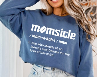 May include: A blue sweatshirt with a white graphic that says "momsicle /mam-si-kuh-l/ noun 1. one who stands at an icerink and freezes for the love of her child"