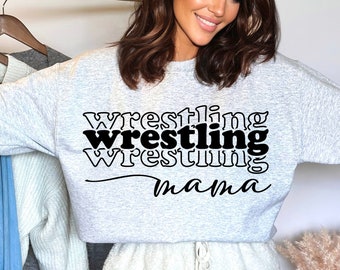 Może przedstawiać: Szara bluza z napisem "Wrestling Mama" w czarnych literach. Tekst jest ułożony w warstwowym, nakładającym się wzorze.