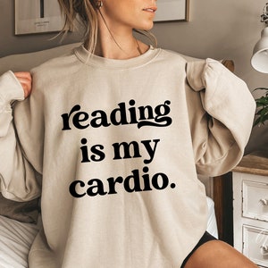 May include: A beige sweatshirt with the text "reading is my cardio." printed in black.